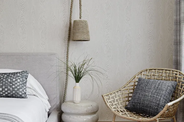 Side table of a guest room with seagrass and a beach styled lamp and chair