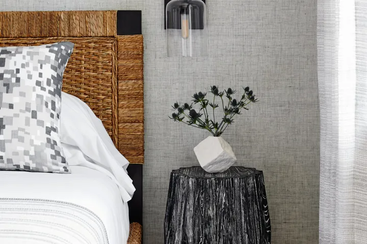 Bedside table with a plant on top and a sconce above it